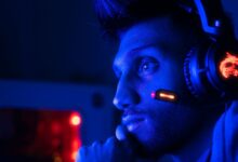 Close-up of a focused gamer with headset in blue lighting, embodying intense concentration.