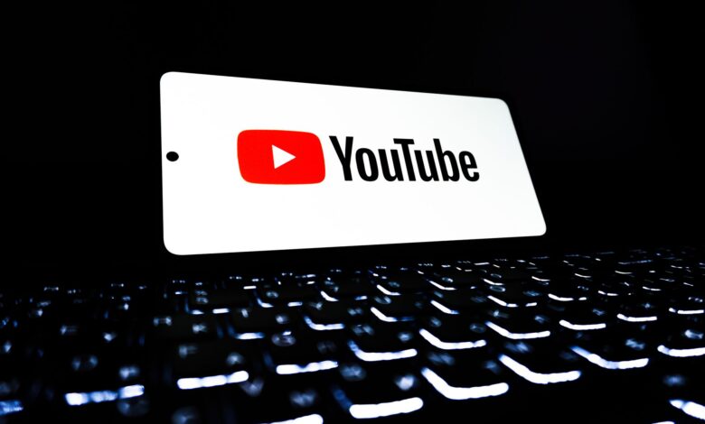 YouTube app icon displayed on a smartphone over an illuminated keyboard, representing digital media and online streaming.
