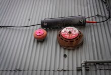 An industrial fire alarm system mounted on a corrugated metal wall for safety and security.
