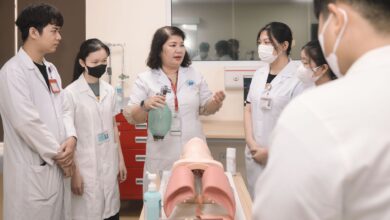 Group of medical students practicing skills with a training mannequin in a classroom setting.