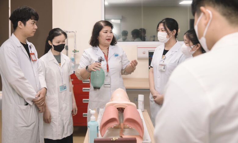 Group of medical students practicing skills with a training mannequin in a classroom setting.