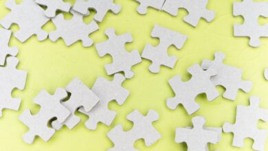 Close-up of gray puzzle pieces scattered on a vibrant yellow background for a playful abstract composition.
