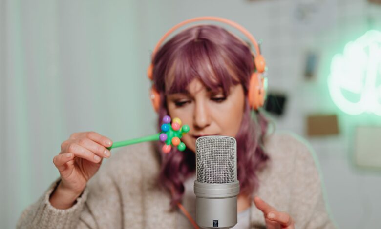 Woman with purple hair recording ASMR using a microphone and colorful props.