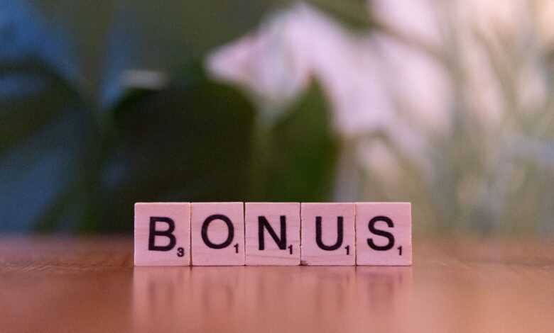 Close-up of the word BONUS spelled with Scrabble tiles on a table.