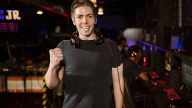 Smiling man with headphones and fist raised, celebrating in a gaming arena.