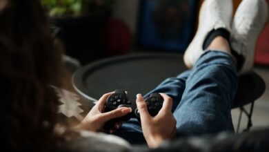 Close-up of woman gaming with a controller, feet propped up, enjoying leisure time indoors.
