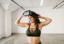 Cheerful woman in sportswear enjoying virtual reality experience indoors.