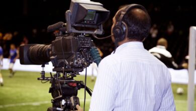 A cameraman filming a soccer match in a stadium, capturing the action on video.