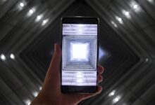 A smartphone screen captures a symmetrically illuminated building interior highlighting modern technology.
