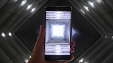 A smartphone screen captures a symmetrically illuminated building interior highlighting modern technology.
