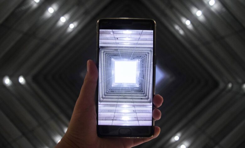 A smartphone screen captures a symmetrically illuminated building interior highlighting modern technology.