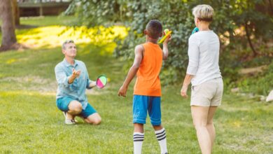 A family enjoying a game of velcro ball in a sunny park, showcasing togetherness and fun.