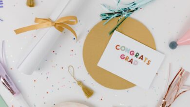 Flat lay of a graduation celebration arrangement with a congrats grad card, tassels, and confetti on a white surface.