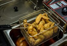 Golden brown chicken wings freshly fried in a commercial deep fryer.