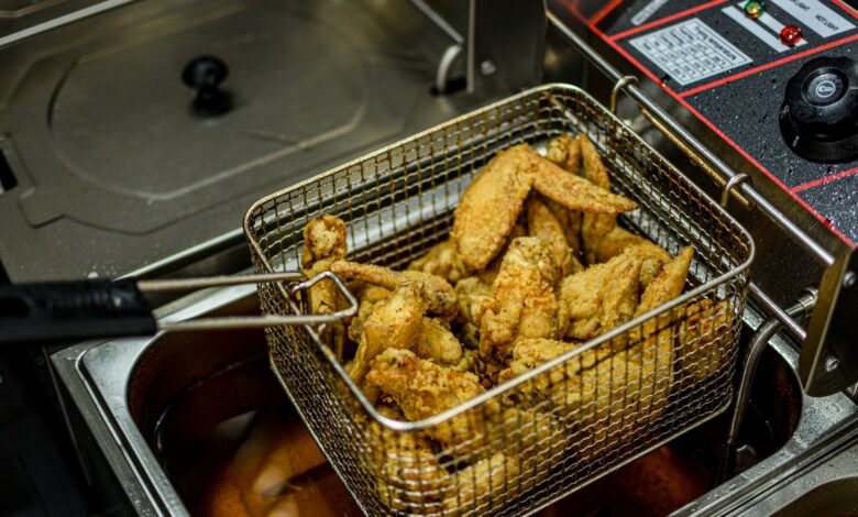 Golden brown chicken wings freshly fried in a commercial deep fryer.