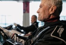 Side view of a senior man in racing gear, participating in indoor kart racing.
