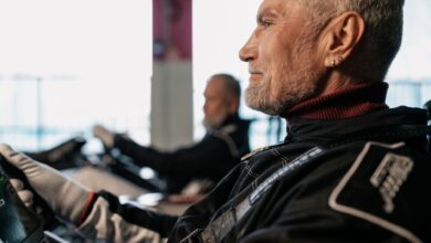 Side view of a senior man in racing gear, participating in indoor kart racing.