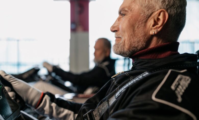 Side view of a senior man in racing gear, participating in indoor kart racing.
