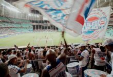 Crowd of enthusiastic fans cheering during a soccer match in a vibrant stadium setting.