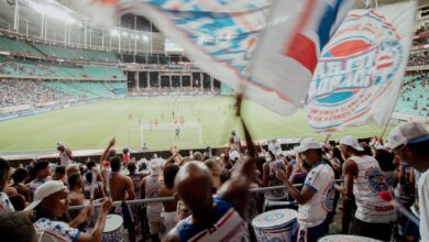 Crowd of enthusiastic fans cheering during a soccer match in a vibrant stadium setting.