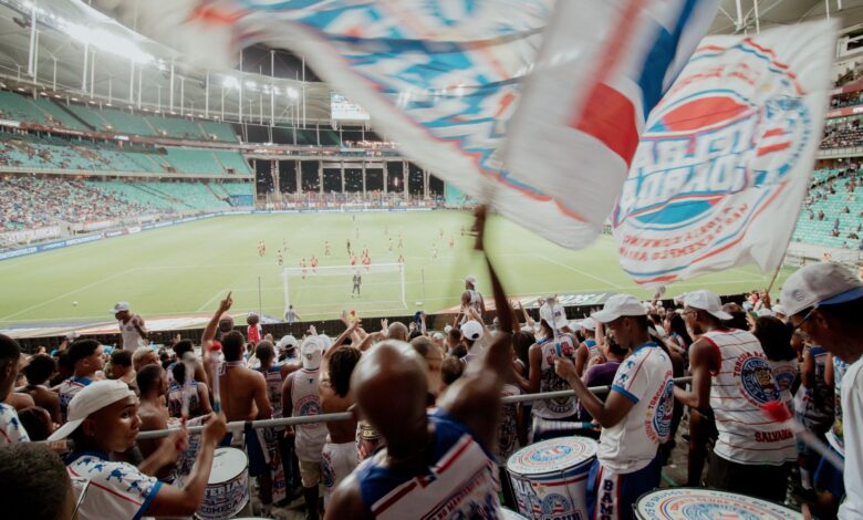 Crowd of enthusiastic fans cheering during a soccer match in a vibrant stadium setting.