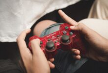 Person playing with a red PlayStation controller, evoking nostalgia for classic gaming.