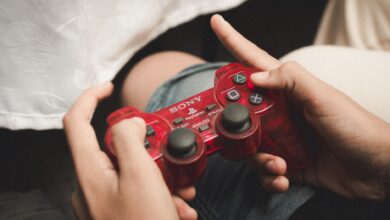 Person playing with a red PlayStation controller, evoking nostalgia for classic gaming.