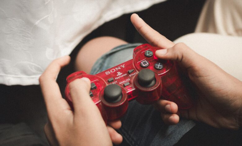 Person playing with a red PlayStation controller, evoking nostalgia for classic gaming.