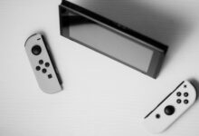 Black and white minimalist flat lay of Nintendo Switch console with game controllers on a white surface.