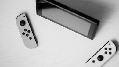 Black and white minimalist flat lay of Nintendo Switch console with game controllers on a white surface.