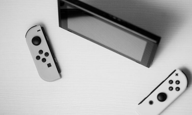 Black and white minimalist flat lay of Nintendo Switch console with game controllers on a white surface.