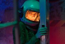A woman astronaut in a helmet inside a sci-fi space vessel, surrounded by colorful lighting.