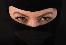 Intense close-up shot of eyes partially covered by a black mask, conveying mystery.