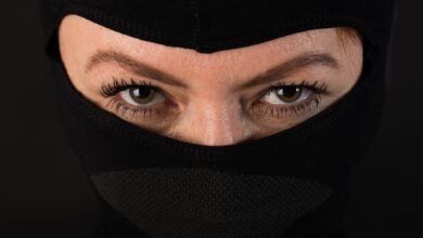 Intense close-up shot of eyes partially covered by a black mask, conveying mystery.