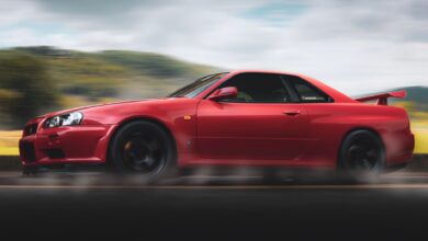 Vibrant red sports car speeds along a scenic highway, showcasing sleek design and performance.