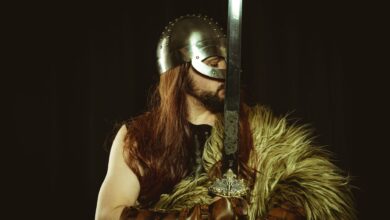 A medieval warrior in full armor, wearing a helmet and holding a large sword.