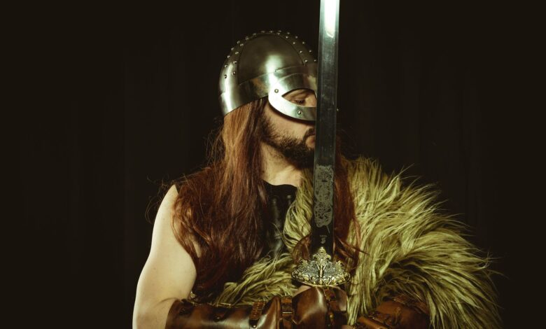 A medieval warrior in full armor, wearing a helmet and holding a large sword.