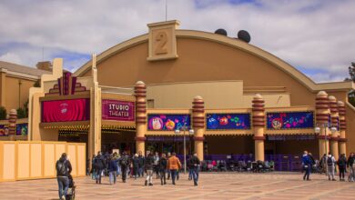 Visitors enter the vibrant Studio Theater entrance at Disneyland Paris on a sunny day.