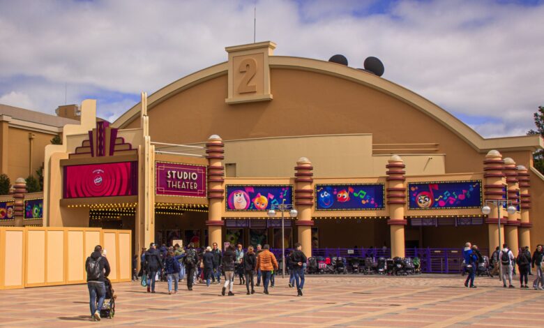 Visitors enter the vibrant Studio Theater entrance at Disneyland Paris on a sunny day.