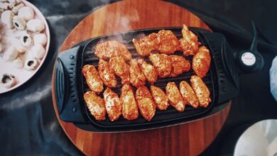 Top view of delicious spicy chicken wings grilling on an electric grill with mushrooms nearby.