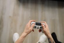 Overhead shot of hands with tattoos holding a game controller, ready for gaming.