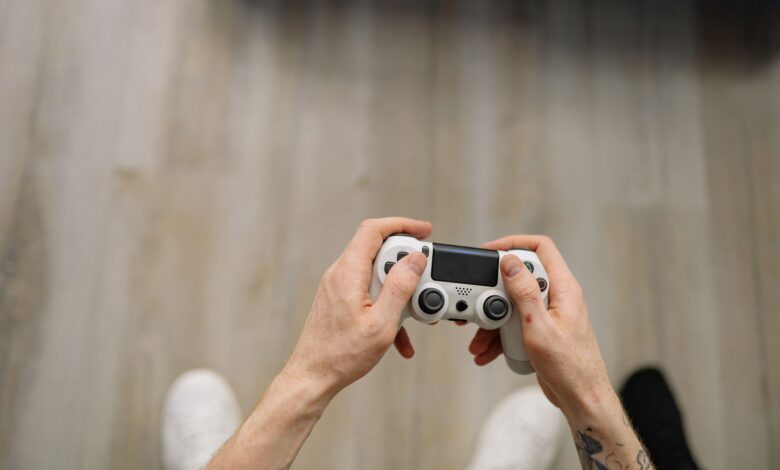 Overhead shot of hands with tattoos holding a game controller, ready for gaming.