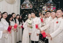 Bride and groom kiss amid festive wedding celebration with traditional attire and confetti.