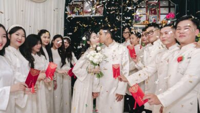 Bride and groom kiss amid festive wedding celebration with traditional attire and confetti.