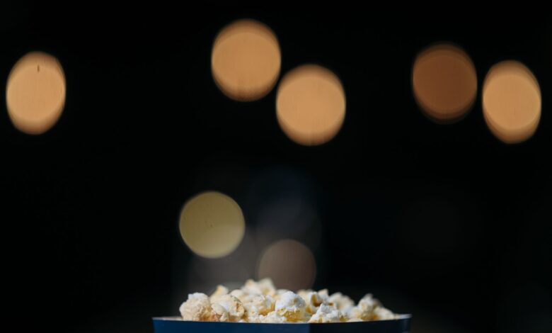 A close-up view of popcorn in a themed bucket with movie bokeh background.