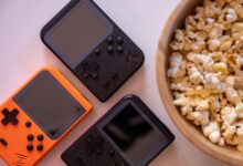 Close-up of retro handheld game consoles and popcorn, perfect for gaming nights.