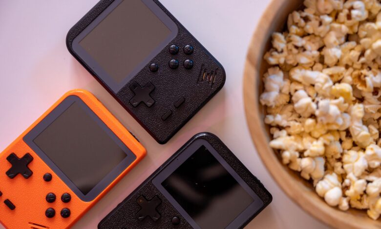 Close-up of retro handheld game consoles and popcorn, perfect for gaming nights.