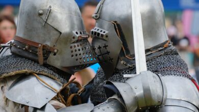 Two medieval knights in full armor engaged in close combat during a reenactment.
