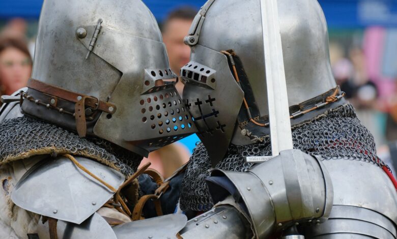 Two medieval knights in full armor engaged in close combat during a reenactment.