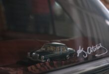 Close-up of a classic car model on display behind glass, featuring signature.